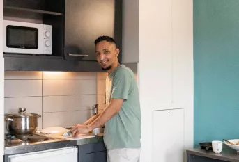 Un jeune résident prépare son repas au sein de la résidence sociale