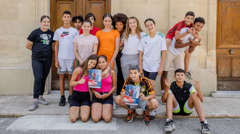 Violette Dorange pose devant le collège au milieu d'une quinzaine de jeunes élèves