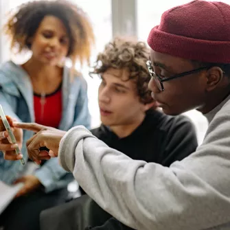 3 jeunes regardant le même smartphone